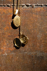 bijou médaillond de forma ovale doré ouvert avec  on s'aime on se le dit on le vit gravé à l'intérieur  ce sont des mots doux de bienveillance et de  partage présenté sur une porte en métal 